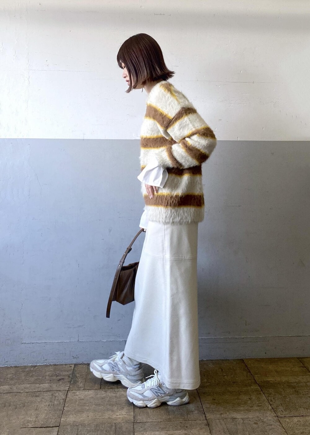 ホワイト系のスカート、ベージュ系のニット/セーター、ブラウン系のハンドバッグを着用したレディースの冬コーディネートの4枚目の写真