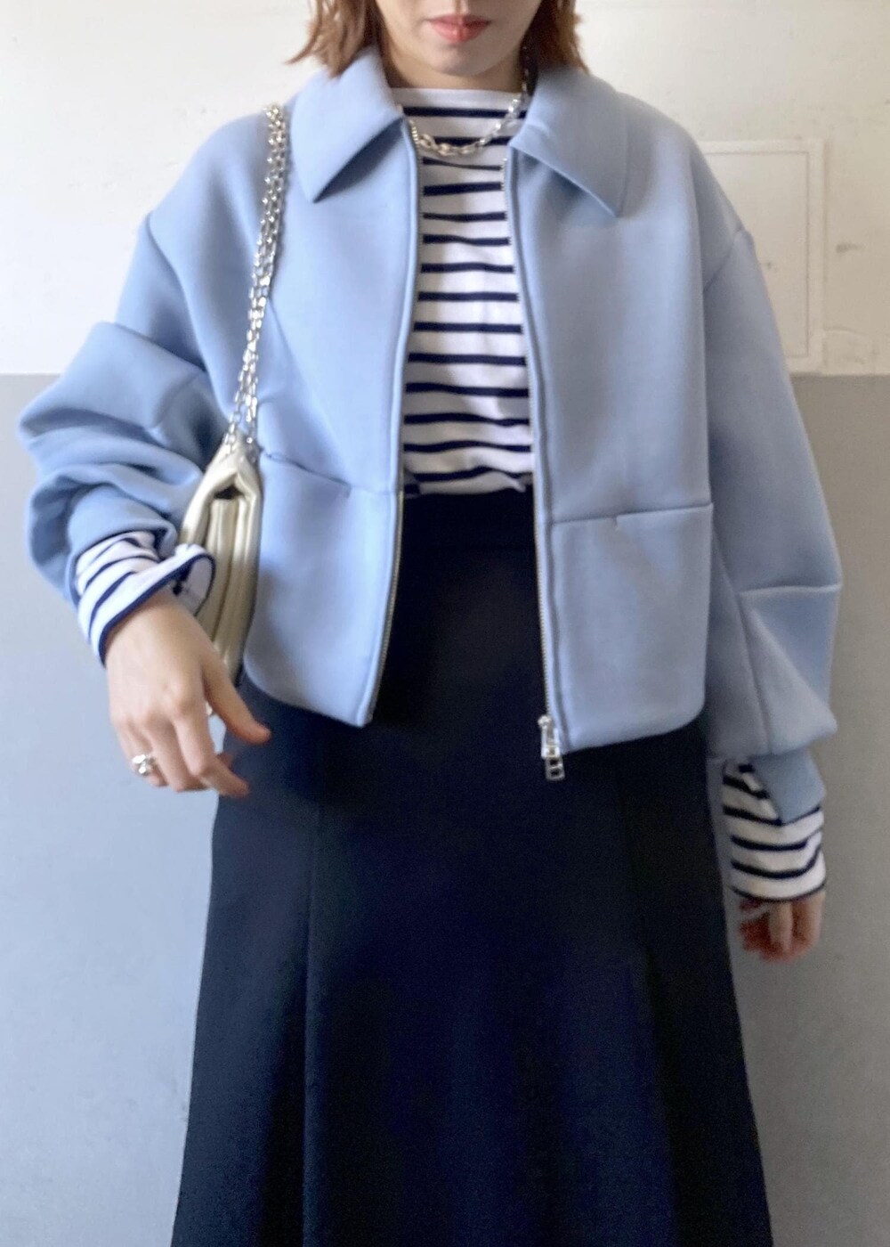 ブラック系のブーツ、ブラック系のスカート、ホワイト系のショルダーバッグを着用したレディースの秋コーディネートの6枚目の写真