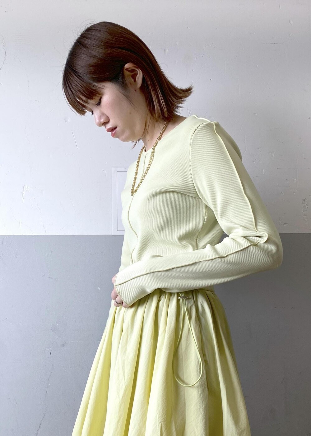 ホワイト系のハンドバッグ、イエロー系のワンピース、ゴールド系のネックレスを着用したレディースの春コーディネートの7枚目の写真