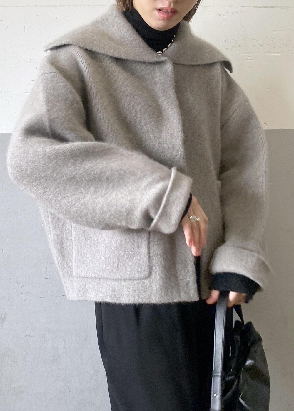 ブラック系のニット/セーター、ベージュ系のカーディガン/ボレロ、ブラック系のハンドバッグを着用したレディースの秋コーディネートの7枚目の写真