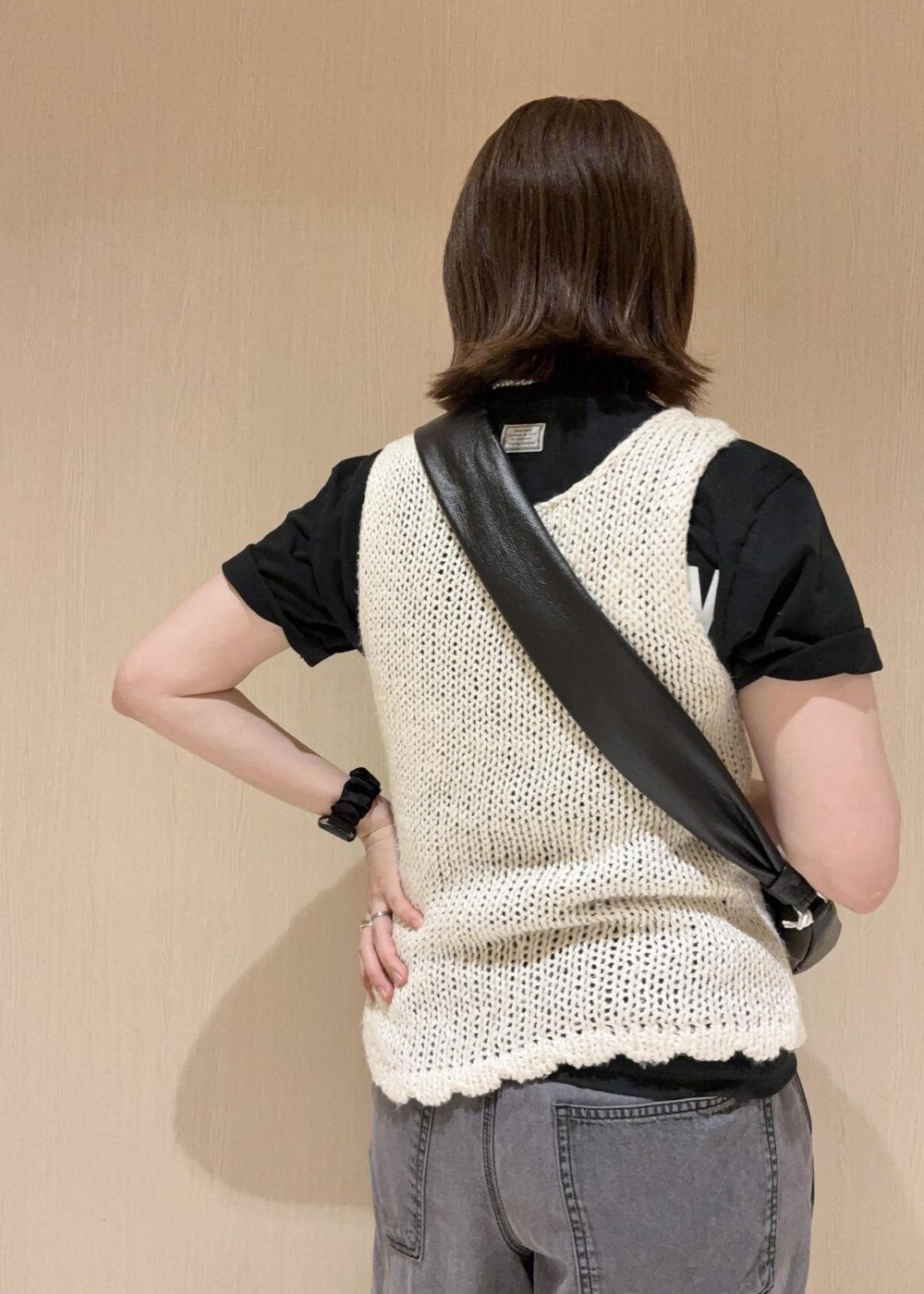 ブラック系のデニムパンツ、ブラック系のショルダーバッグ、ホワイト系のタンクトップを着用したレディースの春コーディネートの7枚目の写真