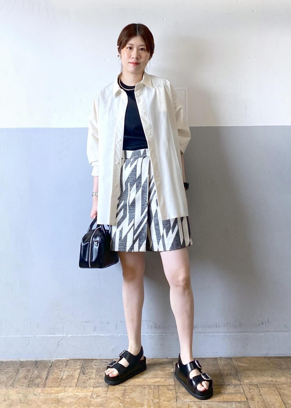 ブラック系のサンダル、ブラック系のボストンバッグ、ブラック系のタンクトップを着用したレディースの春コーディネートの2枚目の写真