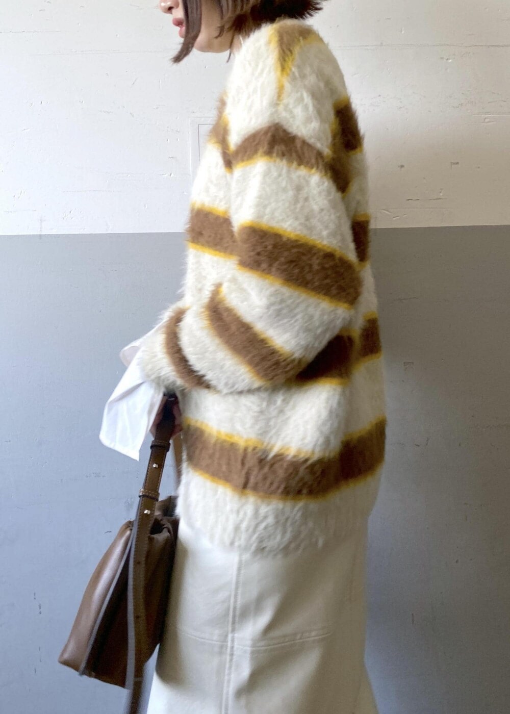 ホワイト系のスカート、ベージュ系のニット/セーター、ブラウン系のハンドバッグを着用したレディースの冬コーディネートの9枚目の写真