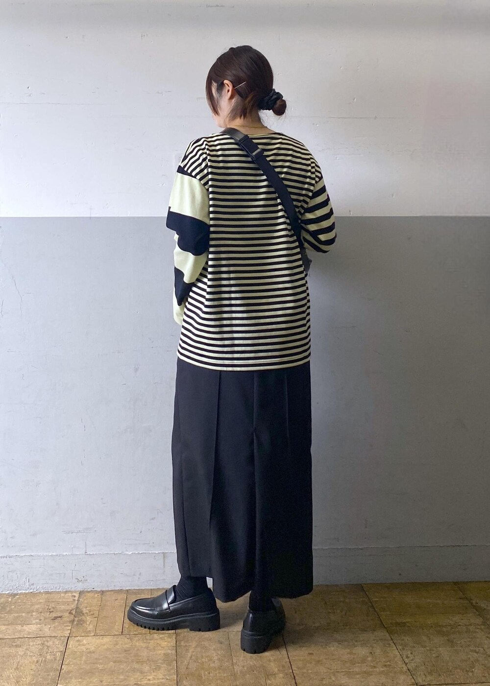 ブラック系のハンドバッグ、ブラック系のローファー、グリーン系のTシャツ/カットソーを着用したレディースの冬コーディネートの5枚目の写真