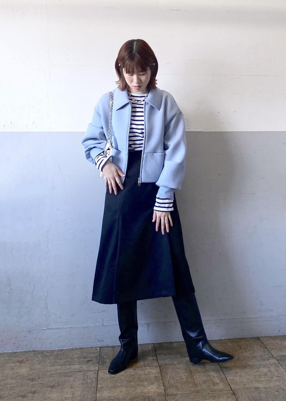 ブラック系のブーツ、ブラック系のスカート、ホワイト系のショルダーバッグを着用したレディースの秋コーディネートの3枚目の写真