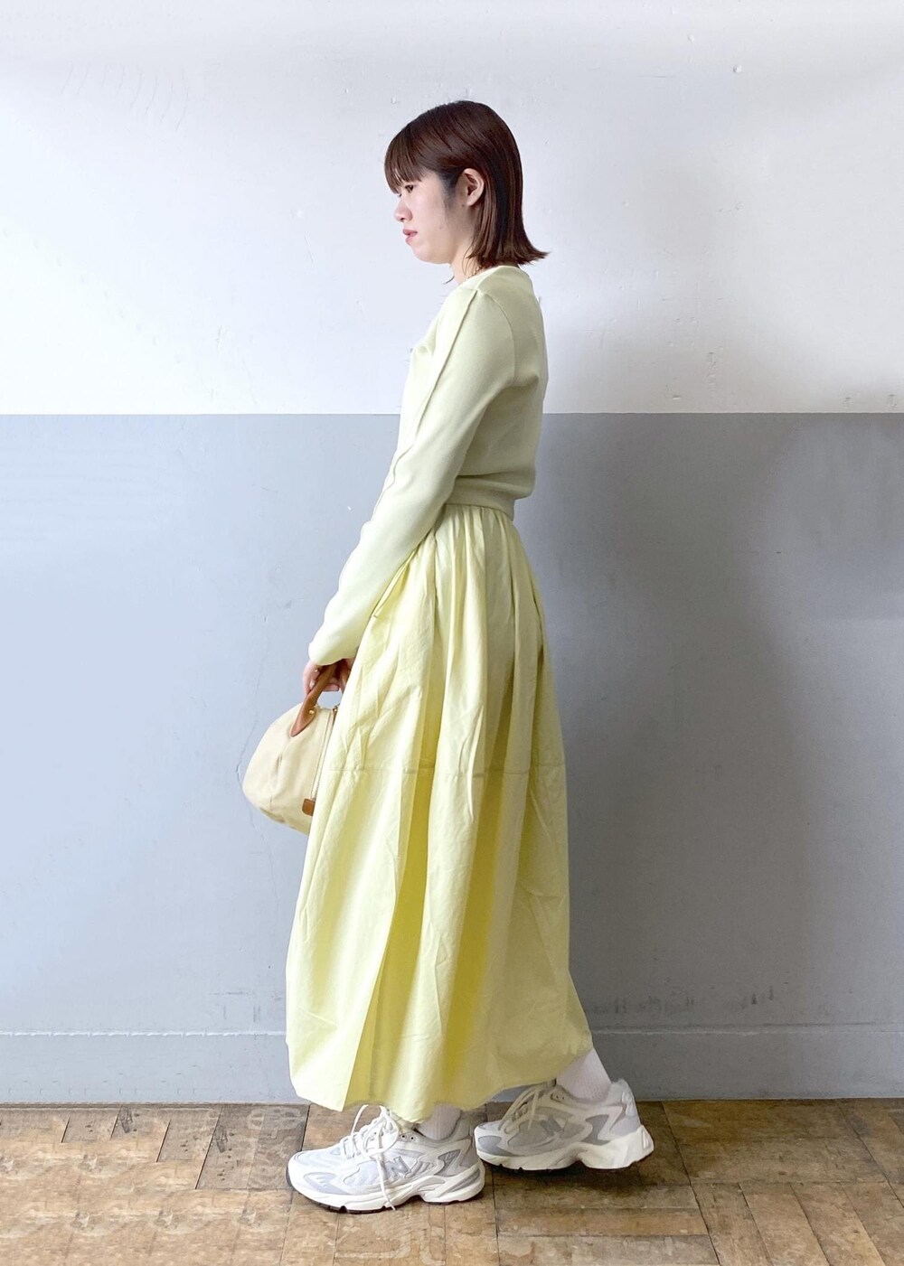 ホワイト系のハンドバッグ、イエロー系のワンピース、ゴールド系のネックレスを着用したレディースの春コーディネートの4枚目の写真
