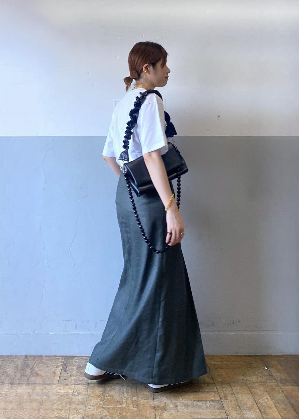 グレー系のスカート、ブラック系のショルダーバッグ、ホワイト系のTシャツ/カットソーを着用したレディースの夏コーディネートの8枚目の写真