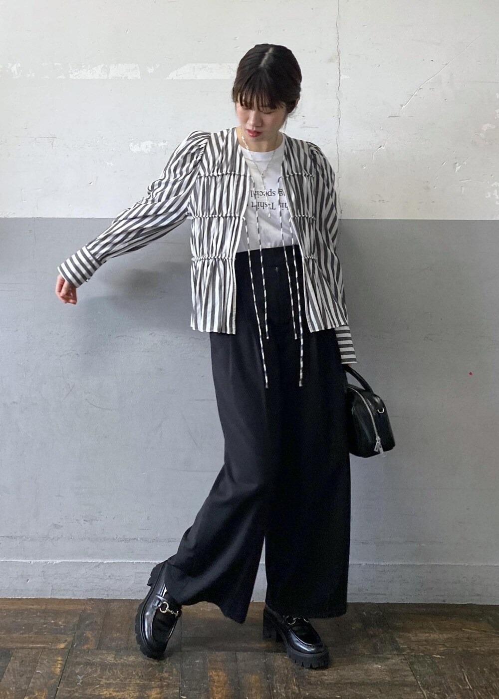 ホワイト系のシャツ/ブラウス、ブラック系のスラックス、ブラック系のボストンバッグを着用したレディースの春コーディネートの2枚目の写真