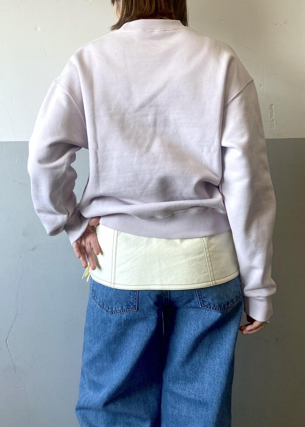 ブラック系のハンドバッグ、パープル系のスウェット、ブルー系のデニムパンツを着用したレディースの冬コーディネートの7枚目の写真