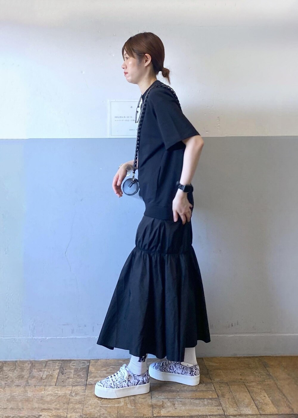 ブラック系のスニーカー、ブラック系のドラムバッグ、ブラック系のワンピースを着用したレディースの夏コーディネートの3枚目の写真