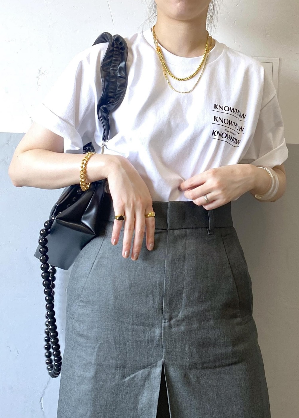 グレー系のスカート、ブラック系のショルダーバッグ、ホワイト系のTシャツ/カットソーを着用したレディースの夏コーディネートの6枚目の写真