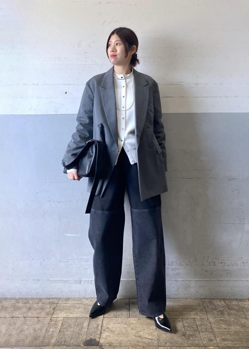 グレー系のテーラードジャケット、ブラック系のパンプス、ブラック系のショルダーバッグを着用したレディースの冬コーディネートの2枚目の写真