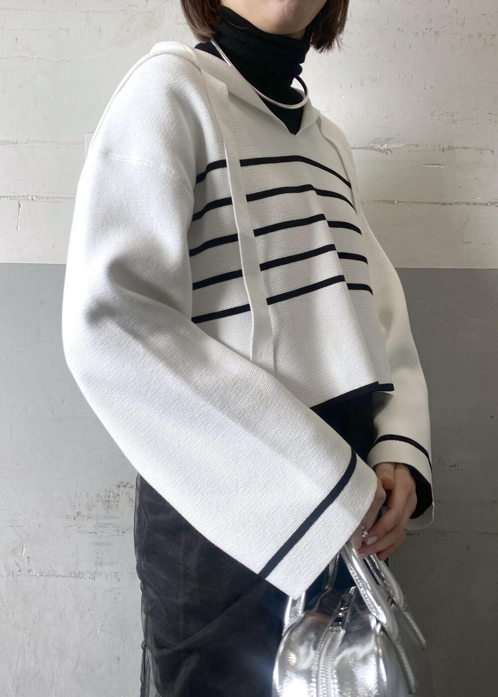 シルバー系のボストンバッグ、ブラック系のニット/セーターを着用したレディースの冬コーディネートの9枚目の写真