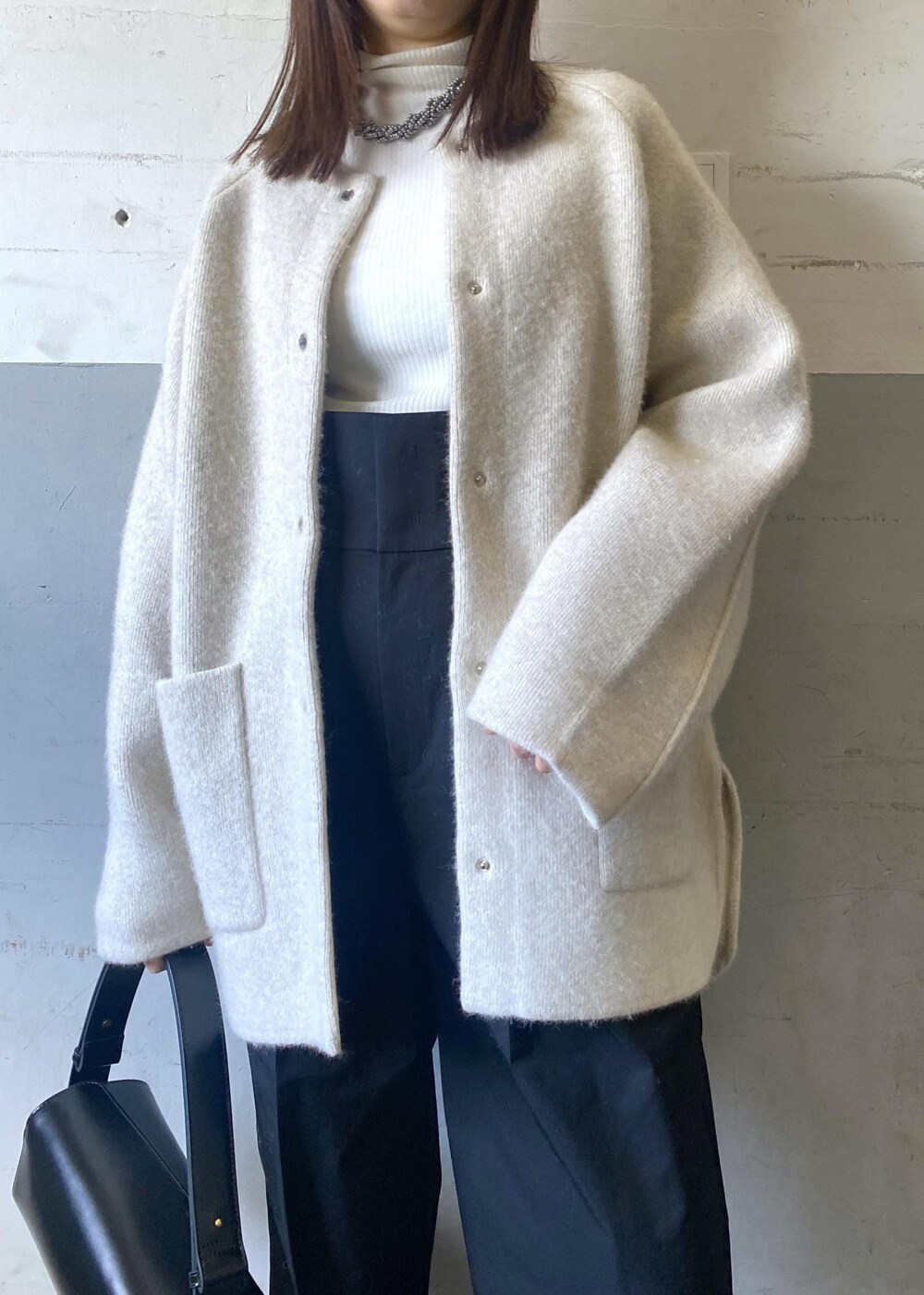 ホワイト系のカーディガン/ボレロ、ホワイト系のニット/セーター、ブラック系のハンドバッグを着用したレディースの冬コーディネートの5枚目の写真