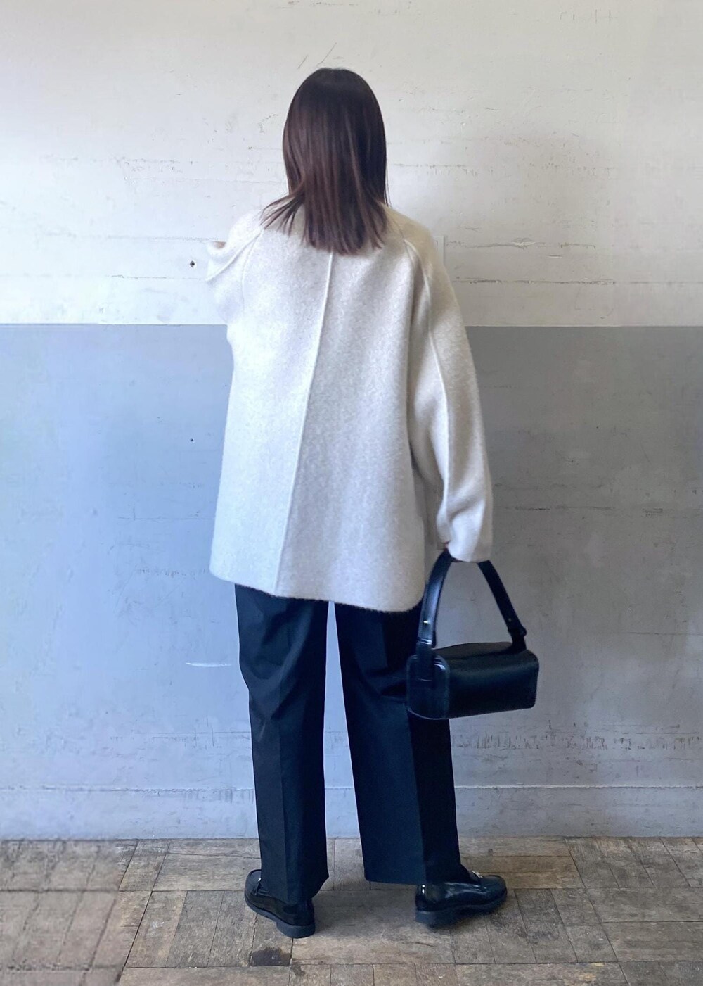 ホワイト系のカーディガン/ボレロ、ホワイト系のニット/セーター、ブラック系のハンドバッグを着用したレディースの冬コーディネートの2枚目の写真