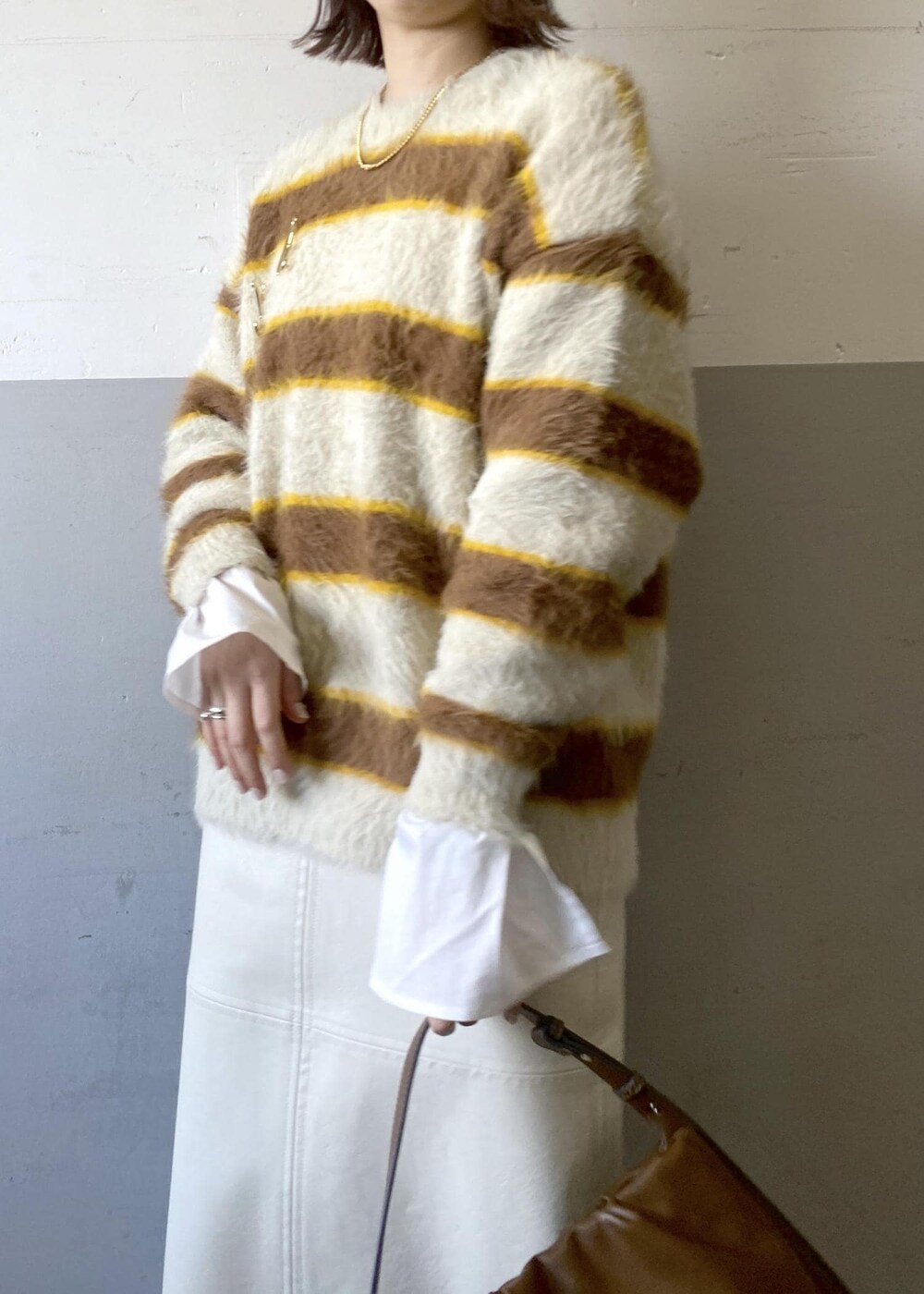 ホワイト系のスカート、ベージュ系のニット/セーター、ブラウン系のハンドバッグを着用したレディースの冬コーディネートの7枚目の写真