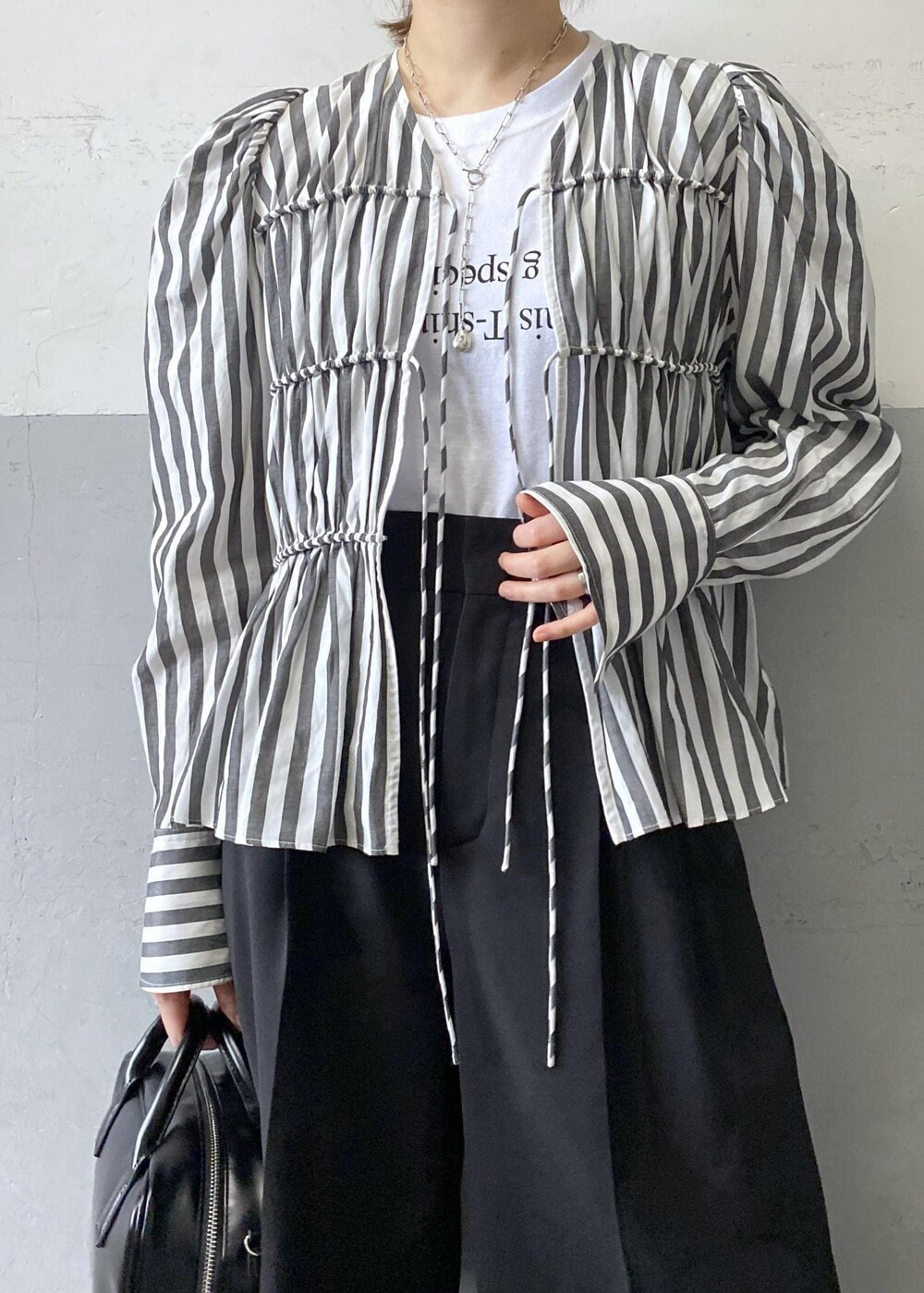 ホワイト系のシャツ/ブラウス、ブラック系のスラックス、ブラック系のボストンバッグを着用したレディースの春コーディネートの7枚目の写真