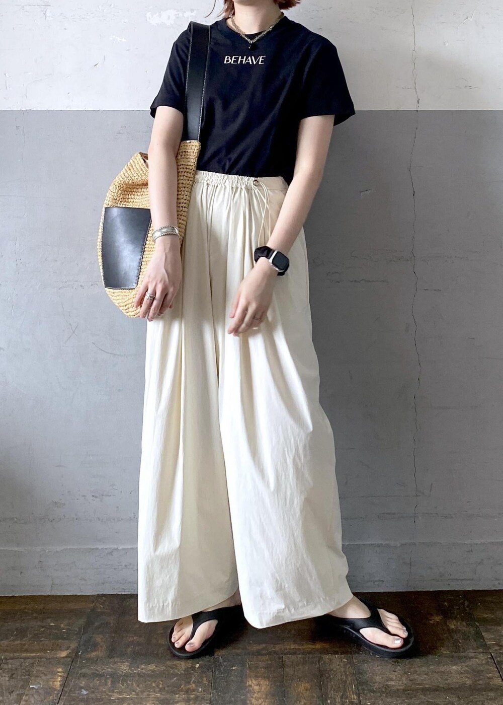 ベージュ系のトートバッグ、ブラック系のTシャツ/カットソー、ブラック系のサンダルを着用したレディースの夏コーディネートの4枚目の写真