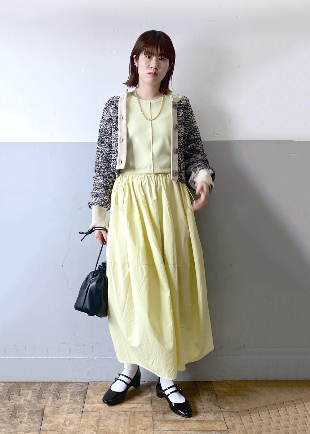 ブラック系のパンプス、ブラック系のショルダーバッグ、ベージュ系のカーディガン/ボレロを着用したレディースの春コーディネートの3枚目の写真