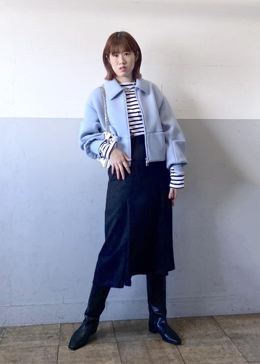 ブラック系のブーツ、ブラック系のスカート、ホワイト系のショルダーバッグを着用したレディースの秋コーディネートの4枚目の写真