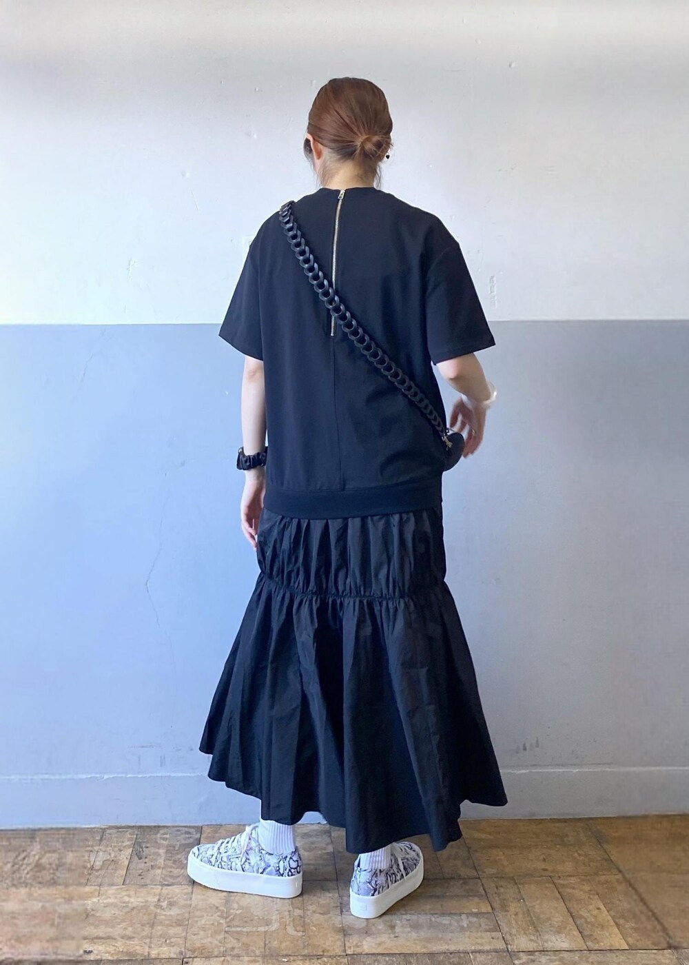 ブラック系のスニーカー、ブラック系のドラムバッグ、ブラック系のワンピースを着用したレディースの夏コーディネートの2枚目の写真