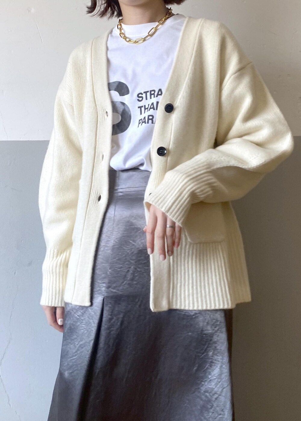 ホワイト系のTシャツ/カットソー、ブラック系のブーツ、ホワイト系のカーディガン/ボレロを着用したレディースの冬コーディネートの5枚目の写真
