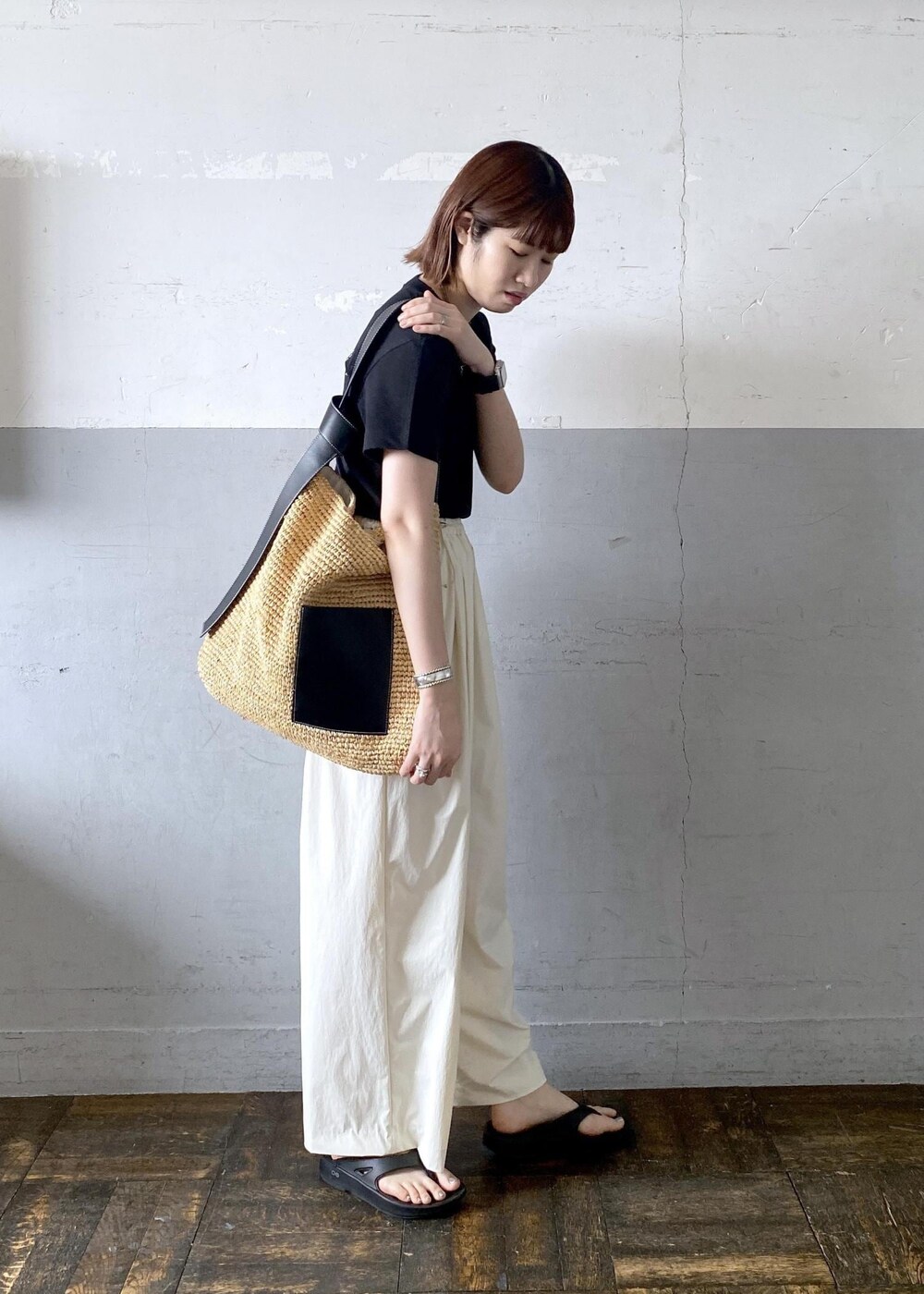 ベージュ系のトートバッグ、ブラック系のTシャツ/カットソー、ブラック系のサンダルを着用したレディースの夏コーディネートの3枚目の写真