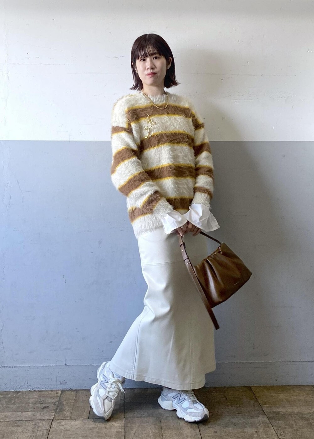 ホワイト系のスカート、ベージュ系のニット/セーター、ブラウン系のハンドバッグを着用したレディースの冬コーディネートの5枚目の写真