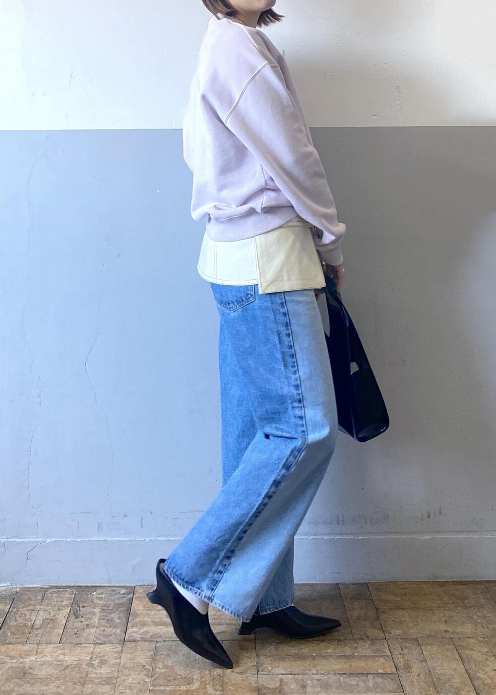 ブラック系のハンドバッグ、パープル系のスウェット、ブルー系のデニムパンツを着用したレディースの冬コーディネートの4枚目の写真