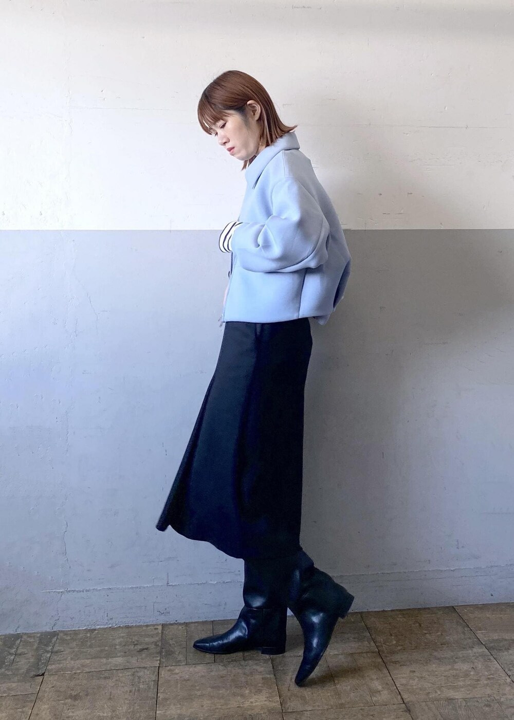 ブラック系のブーツ、ブラック系のスカート、ホワイト系のショルダーバッグを着用したレディースの秋コーディネートの2枚目の写真