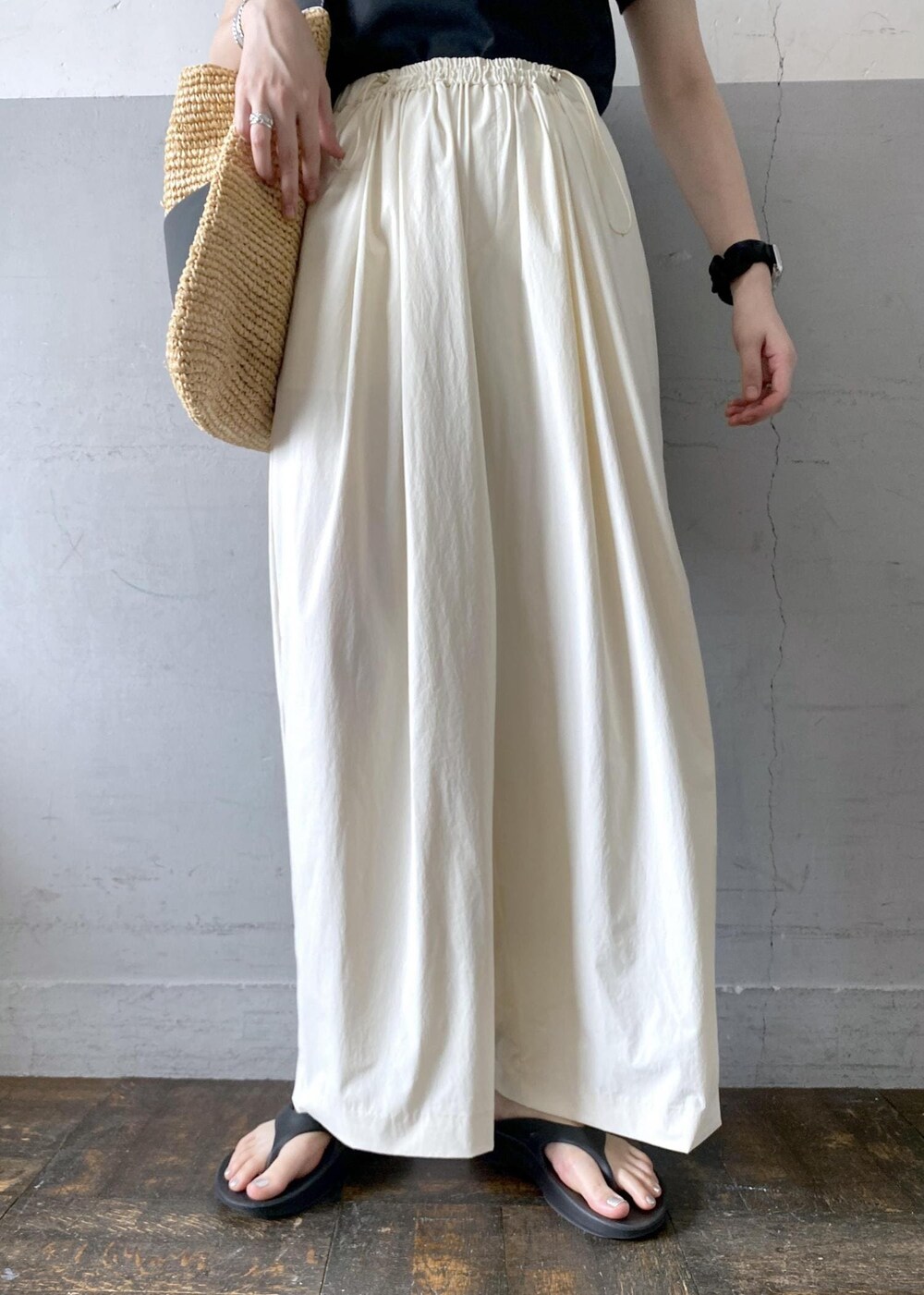 ベージュ系のトートバッグ、ブラック系のTシャツ/カットソー、ブラック系のサンダルを着用したレディースの夏コーディネートの7枚目の写真