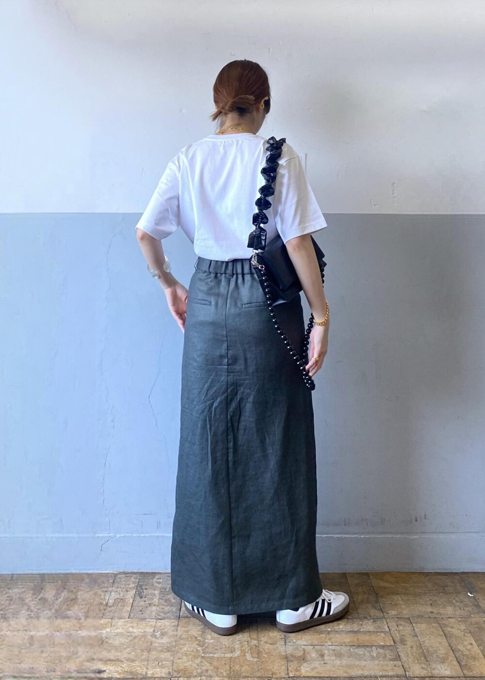 グレー系のスカート、ブラック系のショルダーバッグ、ホワイト系のTシャツ/カットソーを着用したレディースの夏コーディネートの7枚目の写真