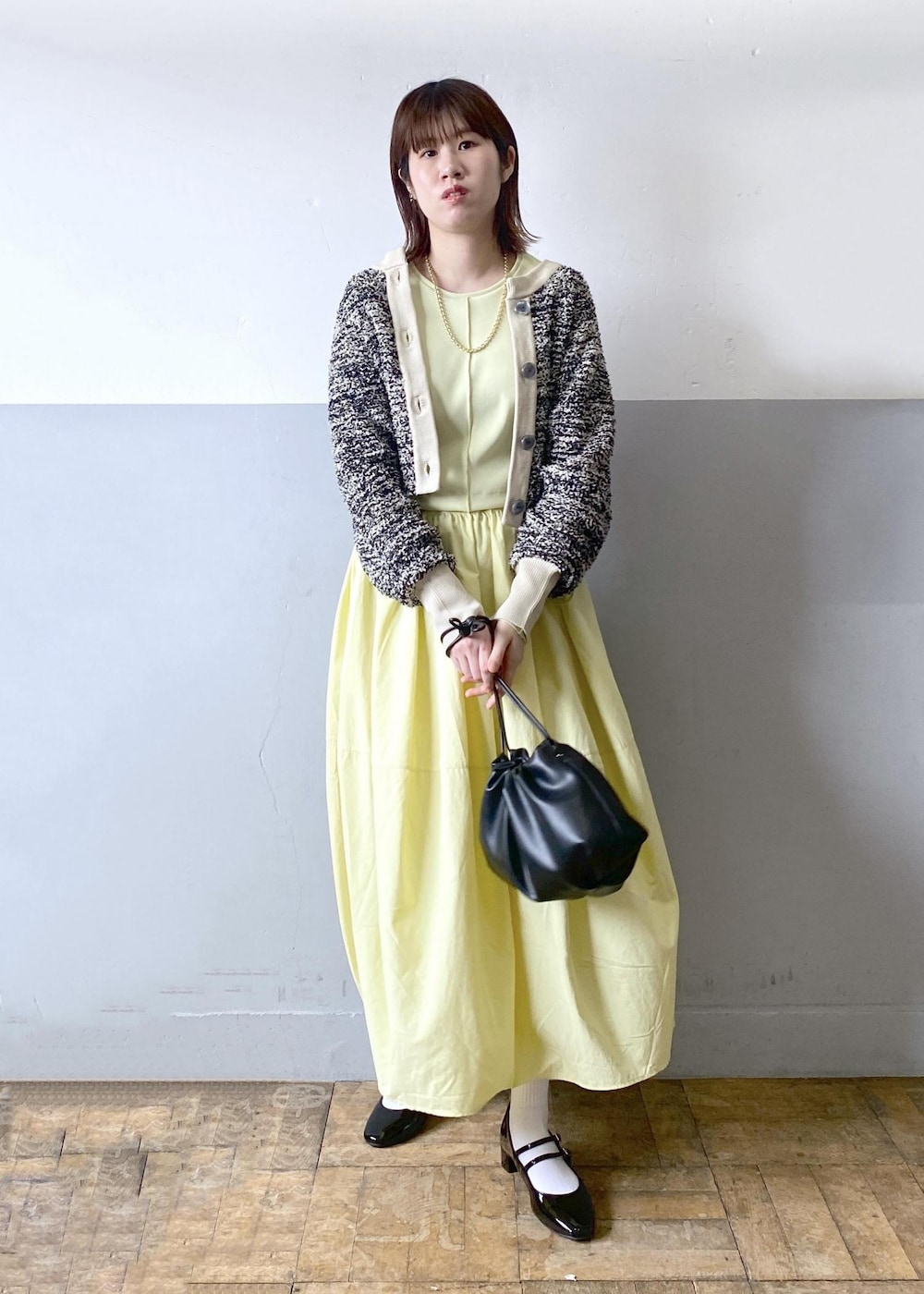 ブラック系のパンプス、ブラック系のショルダーバッグ、ベージュ系のカーディガン/ボレロを着用したレディースの春コーディネートの2枚目の写真