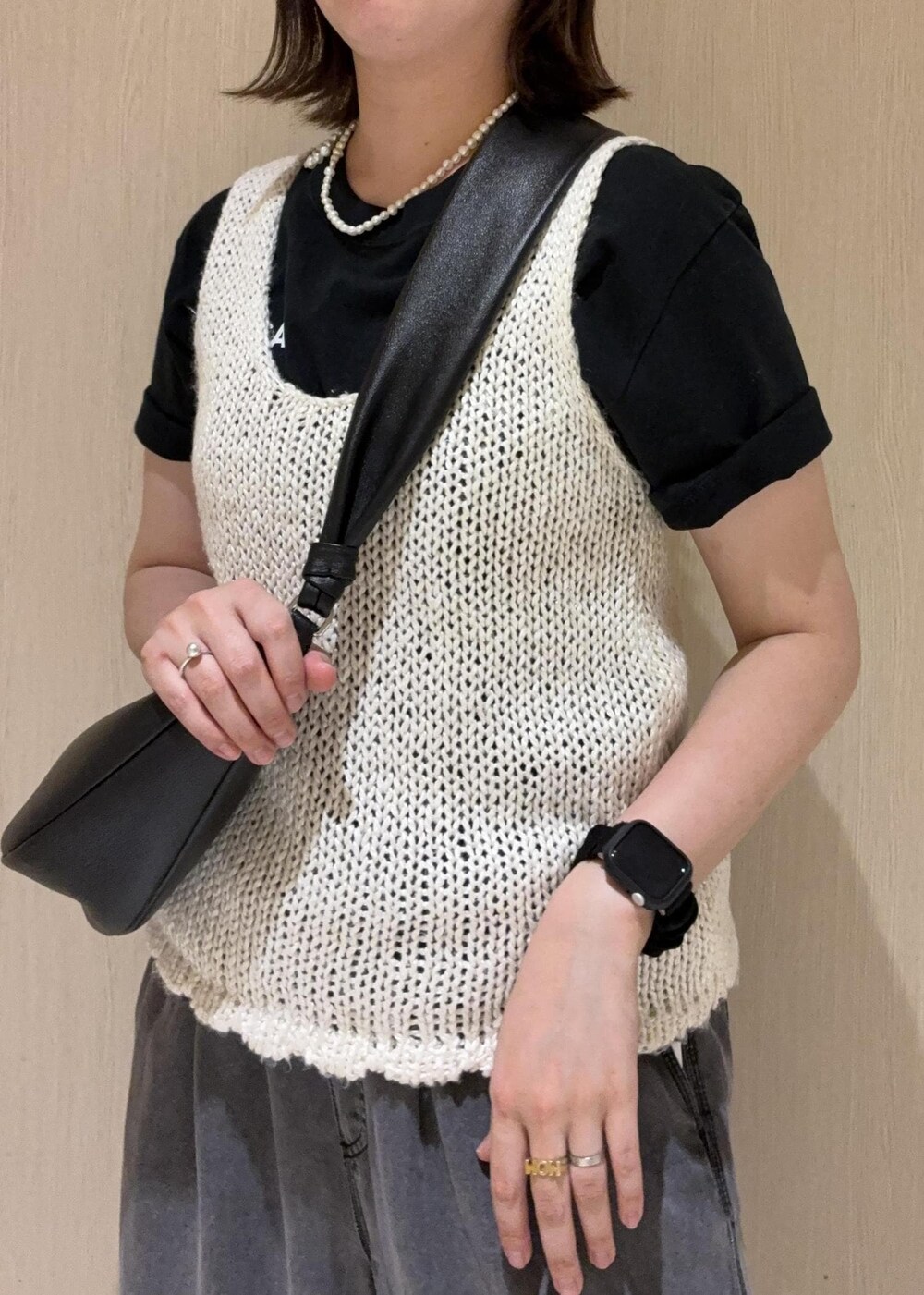 ブラック系のデニムパンツ、ブラック系のショルダーバッグ、ホワイト系のタンクトップを着用したレディースの春コーディネートの5枚目の写真