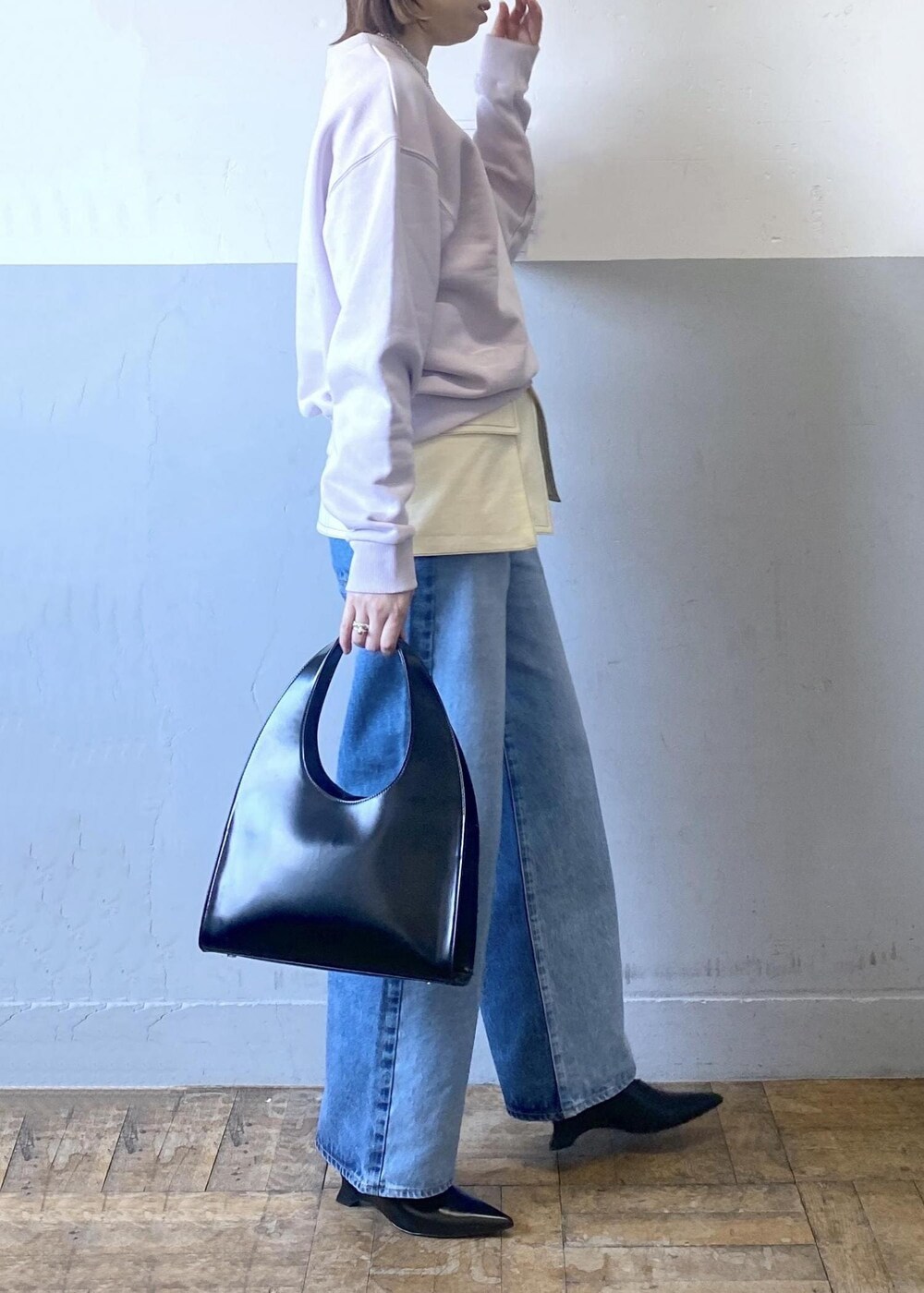 ブラック系のハンドバッグ、パープル系のスウェット、ブルー系のデニムパンツを着用したレディースの冬コーディネートの5枚目の写真