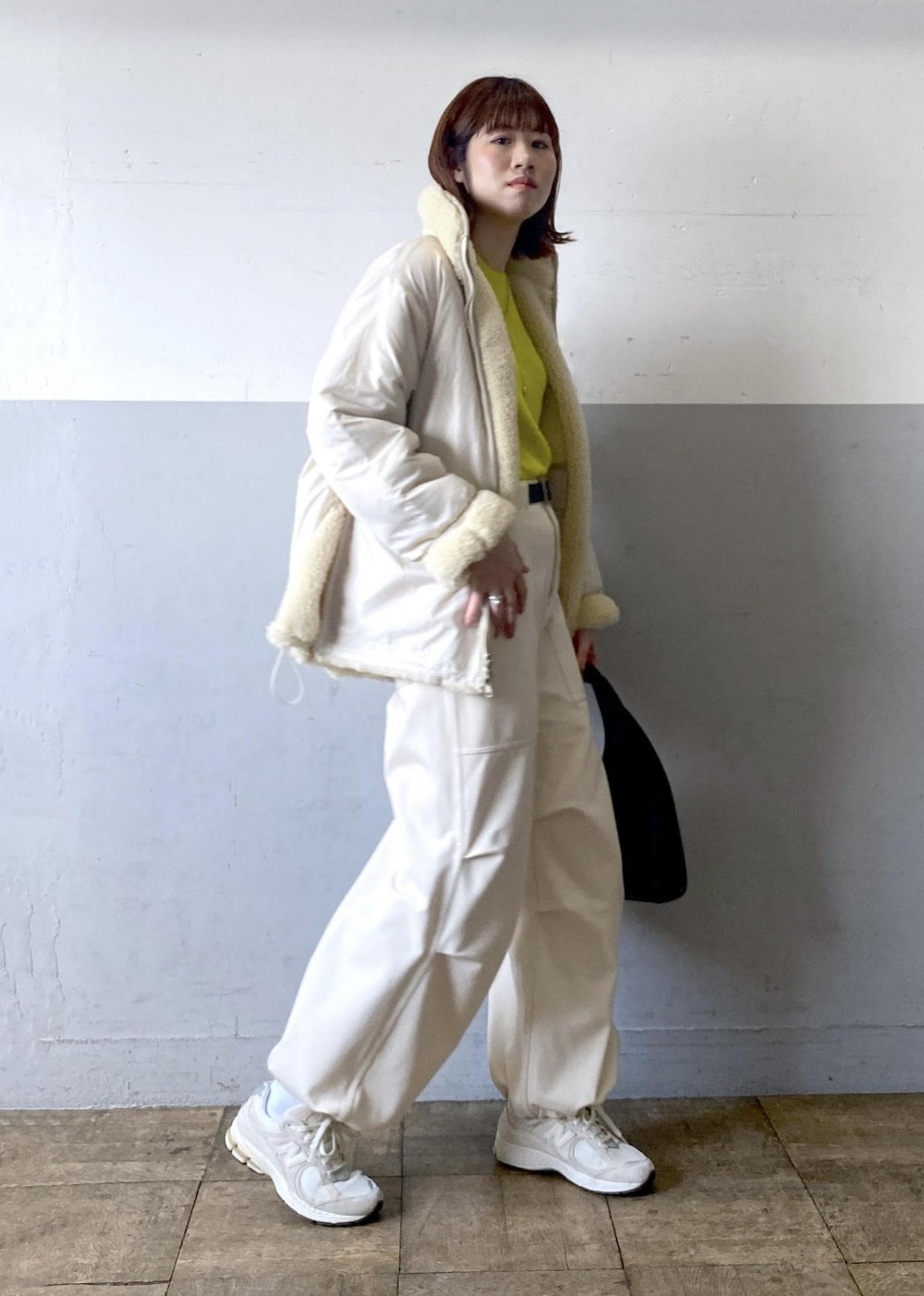 イエロー系のニット/セーター、ブラック系のハンドバッグ、ホワイト系のブルゾンを着用したレディースの秋コーディネートの5枚目の写真