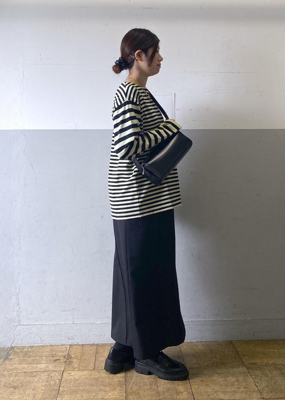 ブラック系のハンドバッグ、ブラック系のローファー、グリーン系のTシャツ/カットソーを着用したレディースの冬コーディネートの3枚目の写真