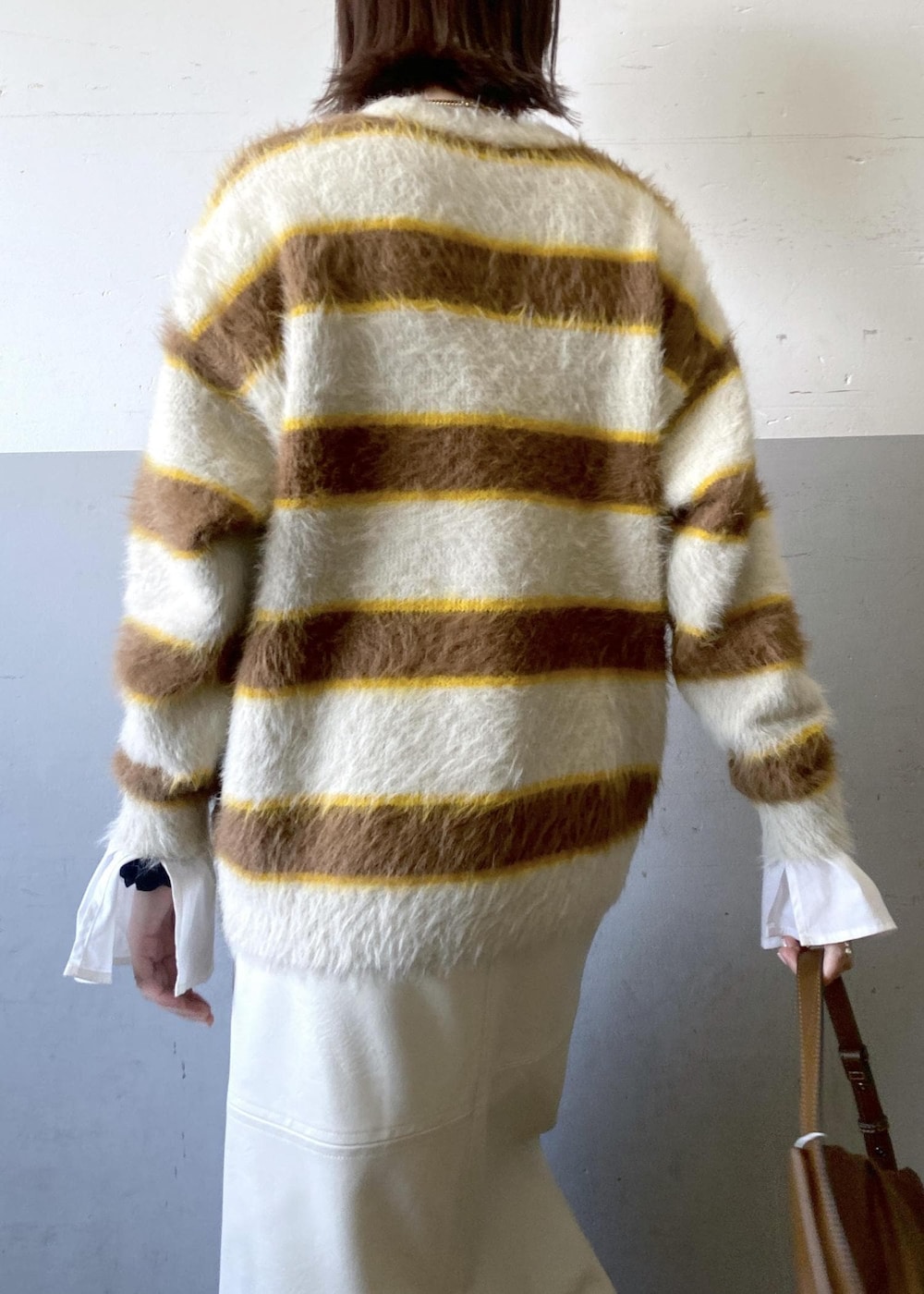 ホワイト系のスカート、ベージュ系のニット/セーター、ブラウン系のハンドバッグを着用したレディースの冬コーディネートの8枚目の写真