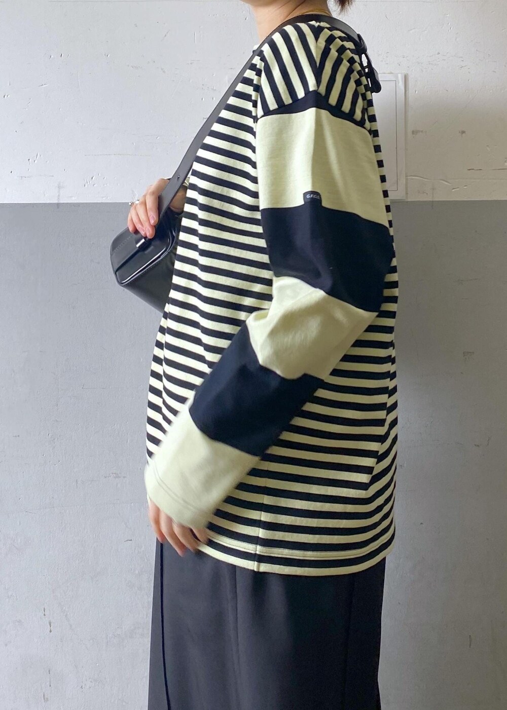 ブラック系のハンドバッグ、ブラック系のローファー、グリーン系のTシャツ/カットソーを着用したレディースの冬コーディネートの6枚目の写真