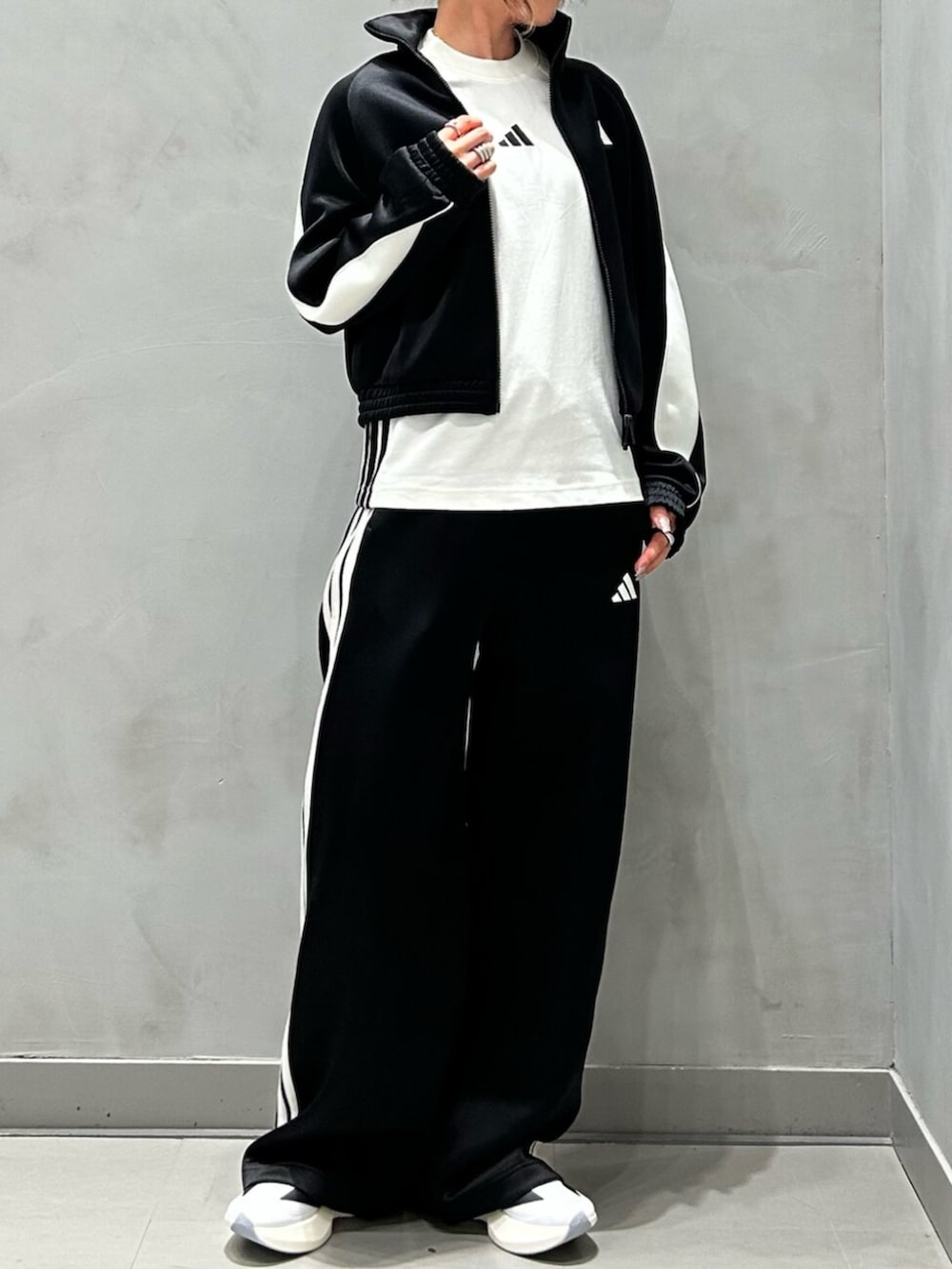 ブラック系のジャージ、ブラック系のスウェットパンツ、ホワイト系のシューズを着用したレディースの秋コーディネートの2枚目の写真