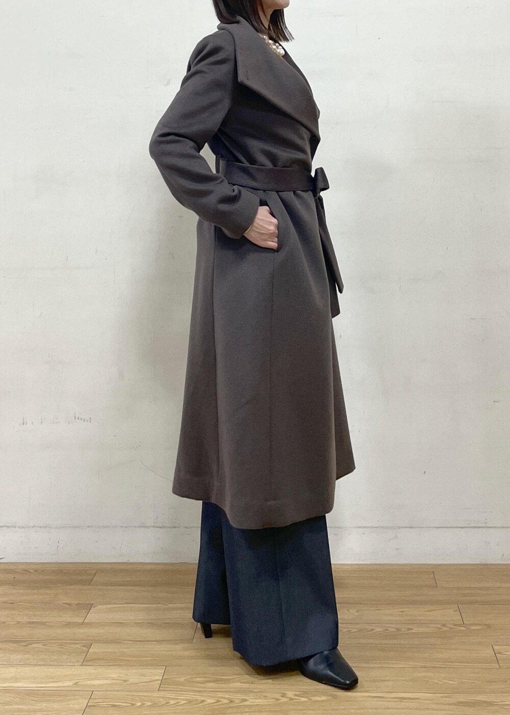 ブラック系のブーツ、ブラウン系のステンカラーコート、ブルー系のその他パンツを着用したレディースの秋コーディネートの8枚目の写真