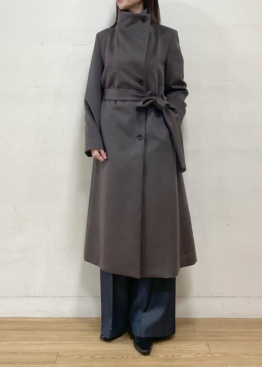 ブラック系のブーツ、ブラウン系のステンカラーコート、ブルー系のその他パンツを着用したレディースの秋コーディネートの2枚目の写真