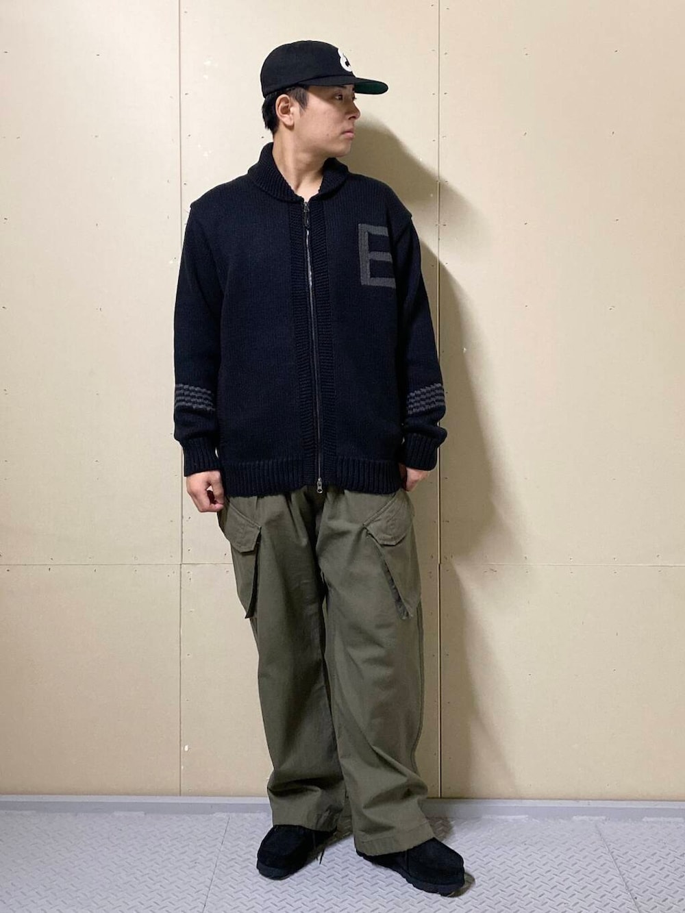 グリーン系のカーゴパンツ、ブラック系のブーツ、ブラック系のニット/セーターを着用したメンズの秋コーディネートの5枚目の写真