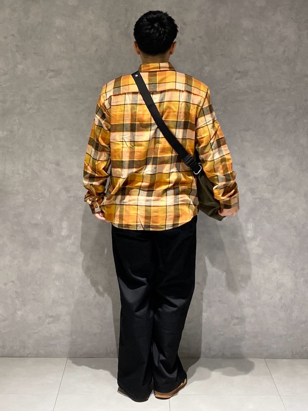 オレンジ系のシャツ/ブラウス、グリーン系のショルダーバッグ、ブラック系のチノパンツを着用したメンズの秋コーディネートの3枚目の写真