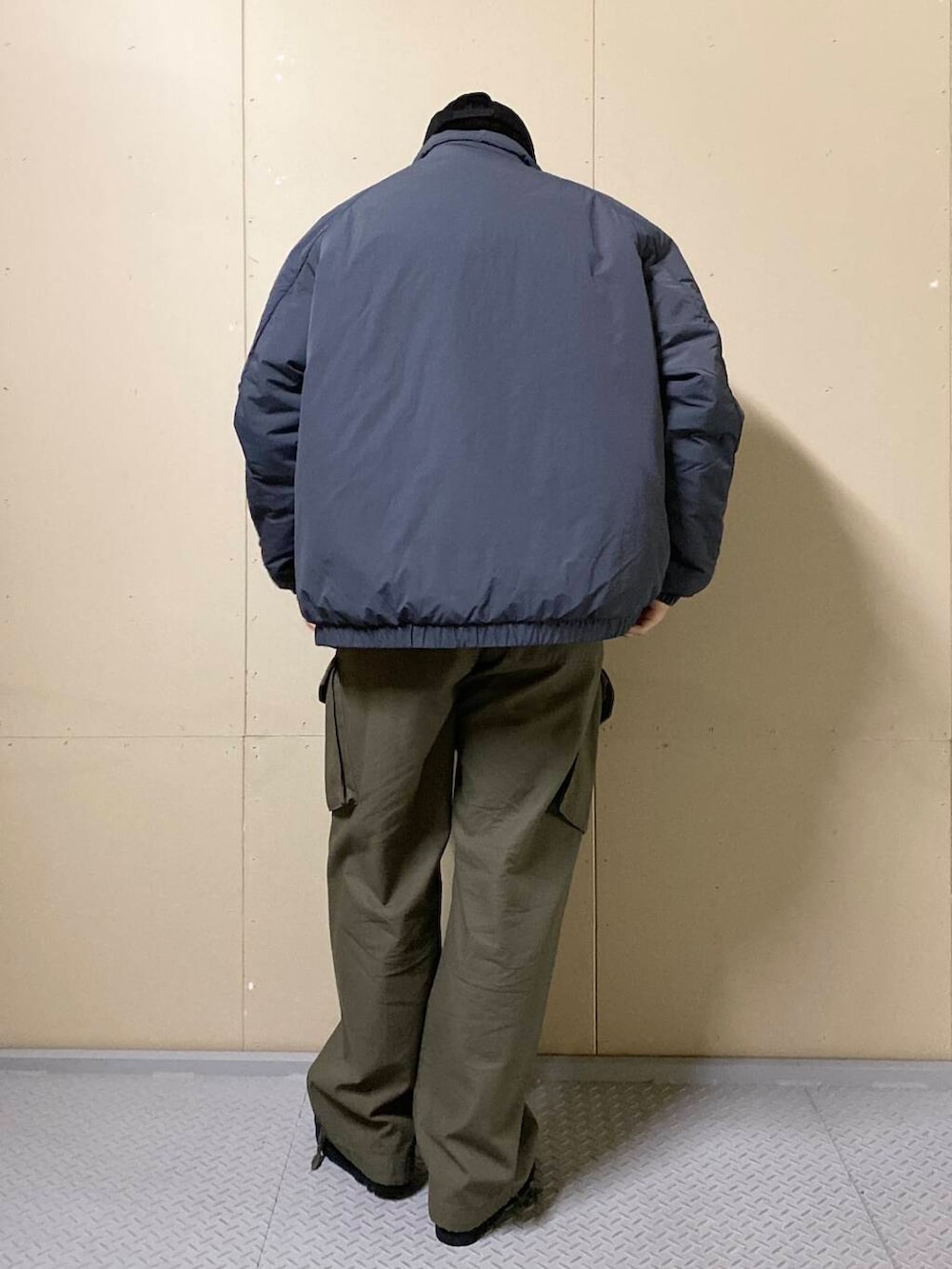 グリーン系のカーゴパンツ、ブラック系のブーツ、ブラック系のニット/セーターを着用したメンズの秋コーディネートの4枚目の写真