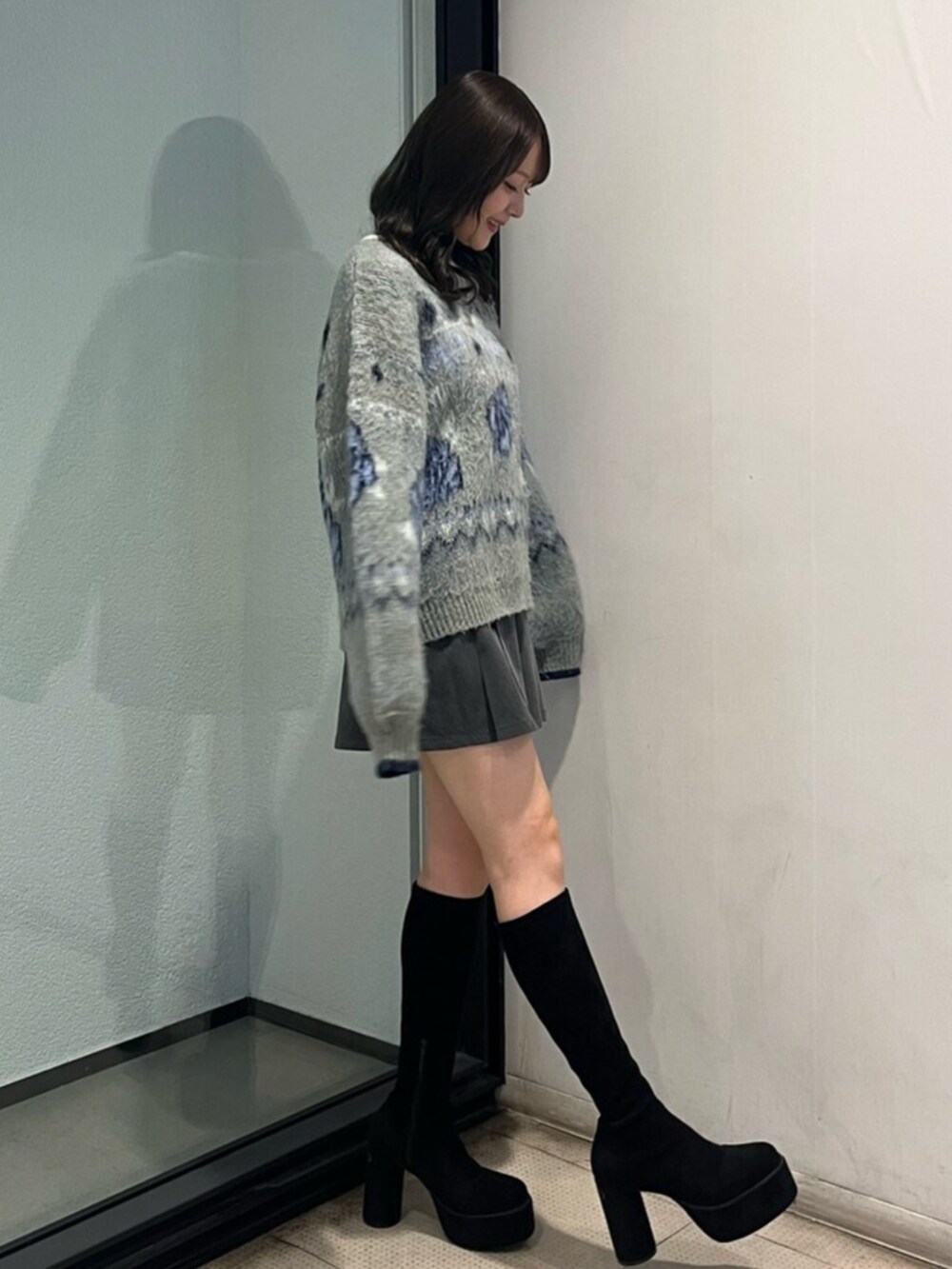 ブラック系のブーツ、グレー系のニット/セーター、グレー系のスカートを着用したレディースの秋コーディネートの2枚目の写真