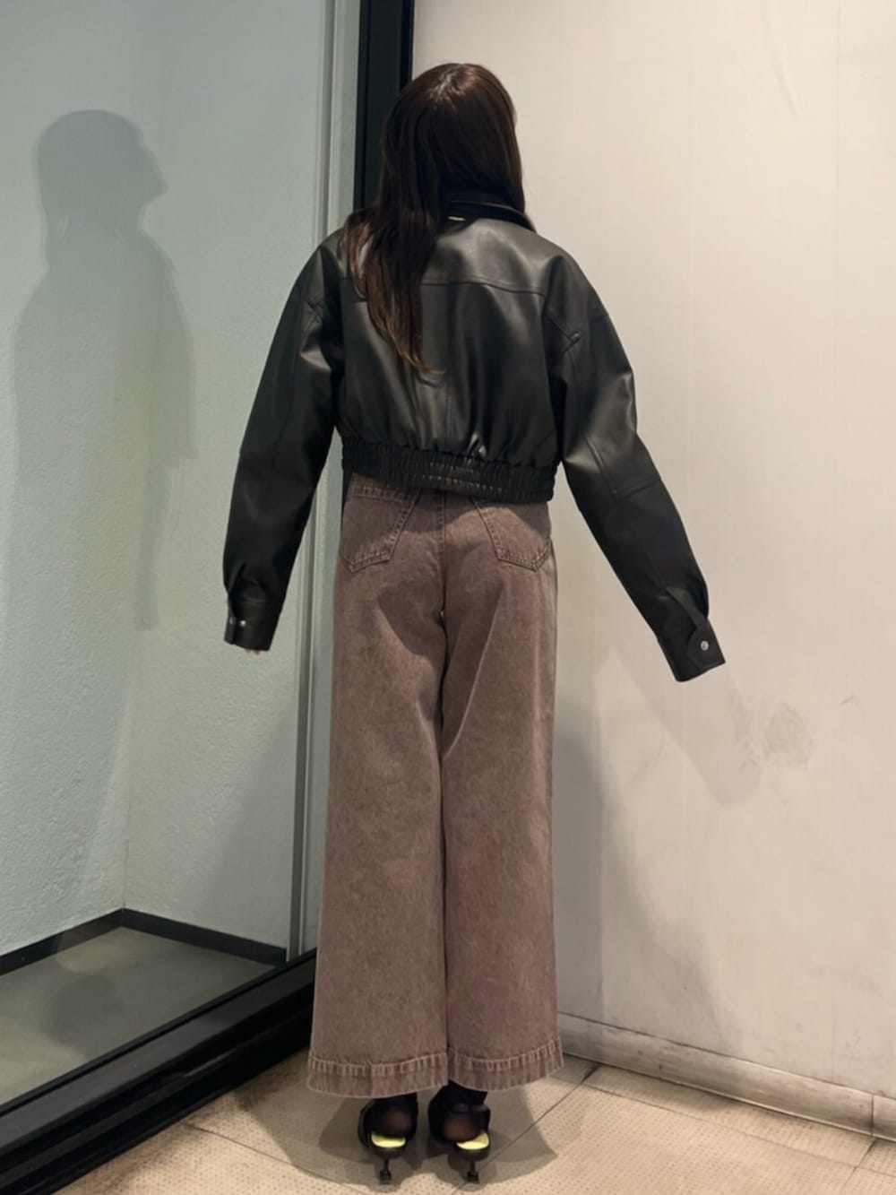 イエロー系のニット/セーター、ブラック系のサンダル、ブラック系のブルゾンを着用したレディースの春コーディネートの3枚目の写真