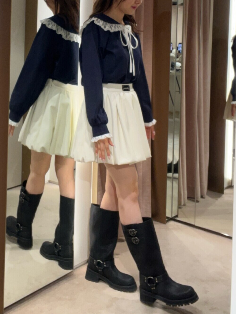 ブラック系のブーツ、ブルー系のTシャツ/カットソー、ホワイト系のスカートを着用したレディースの秋コーディネートの2枚目の写真