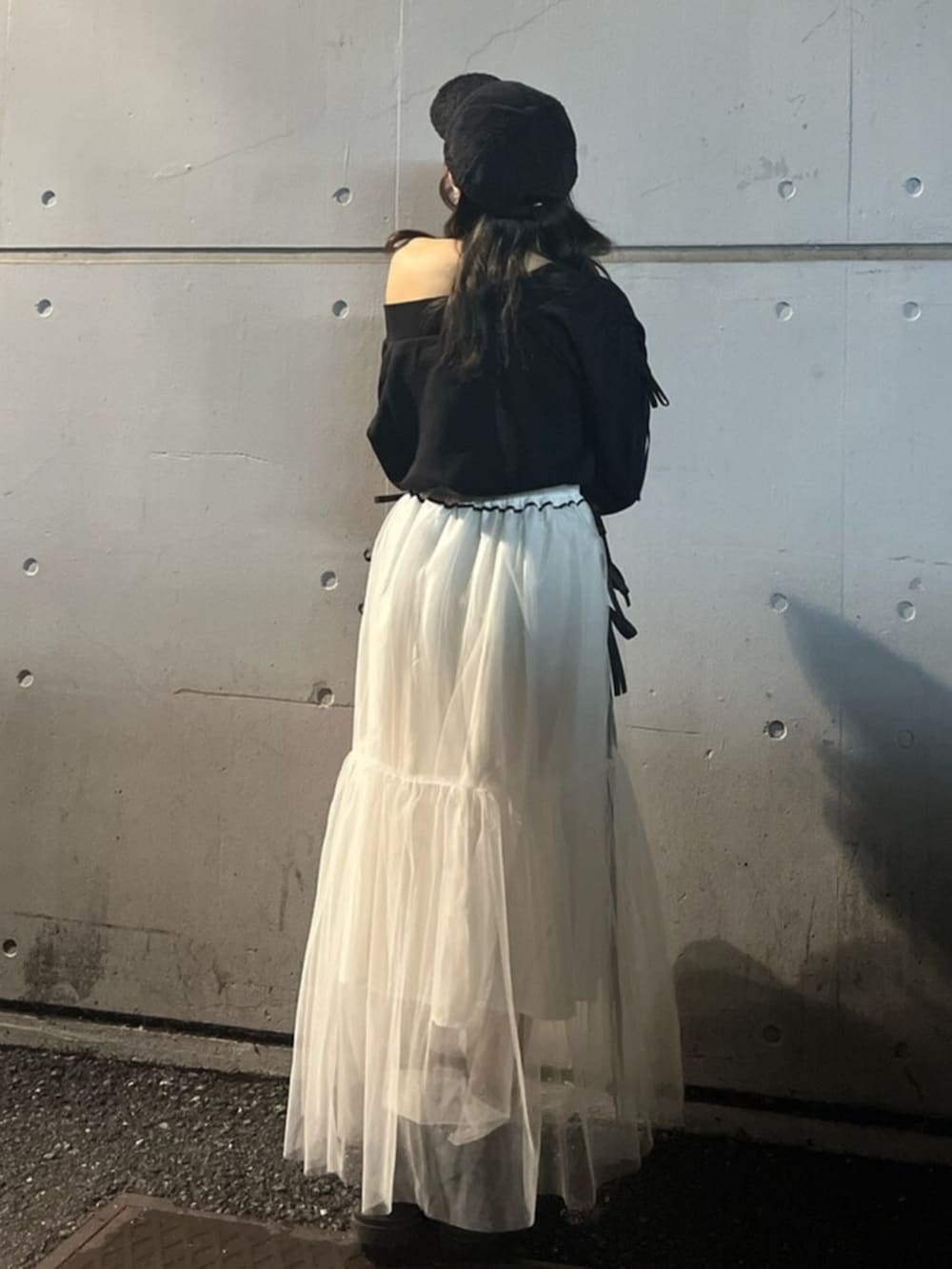 ブラック系のスウェット、ホワイト系のスカート、ブラック系のキャップを着用したレディースの秋コーディネートの3枚目の写真