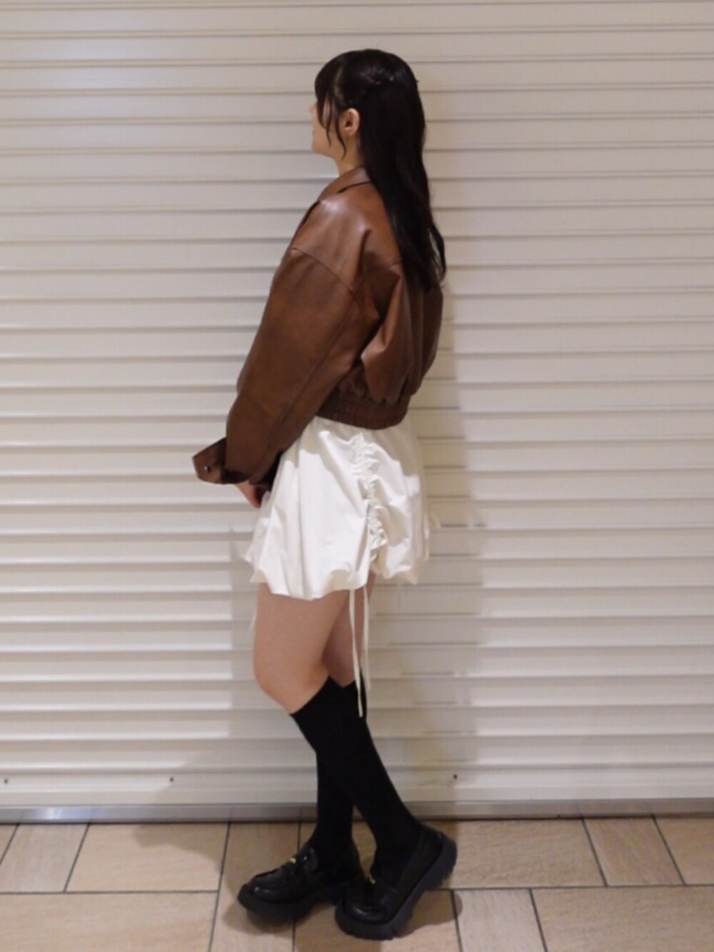 ブラウン系のブルゾン、ホワイト系のスカートを着用したレディースの冬コーディネートの2枚目の写真